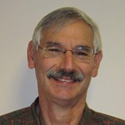 Headshot of Andrew. He has grey hair, glasses, and a mustache.