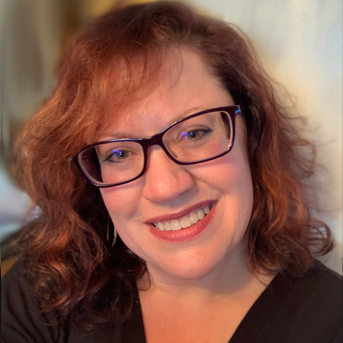 The image shows a headshot of Sarah Farmer with shoulder-length wavy red hair, wearing glasses, and smiling. They are dressed in a dark top, and the background appears to be softly blurred.